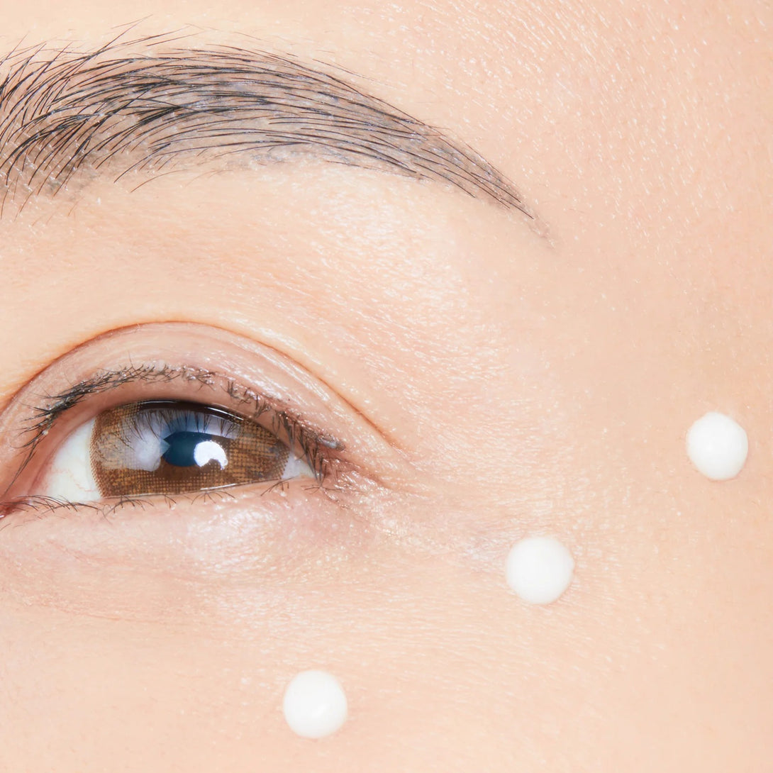 Close-up of a person's eye with droplets on the skin around it.