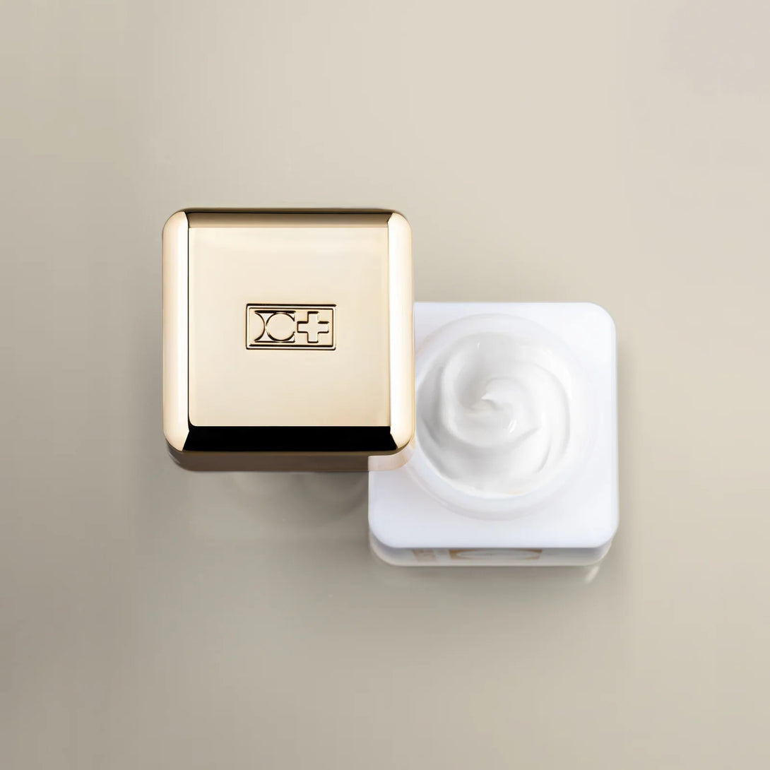 Gold and white cosmetic product on a beige background