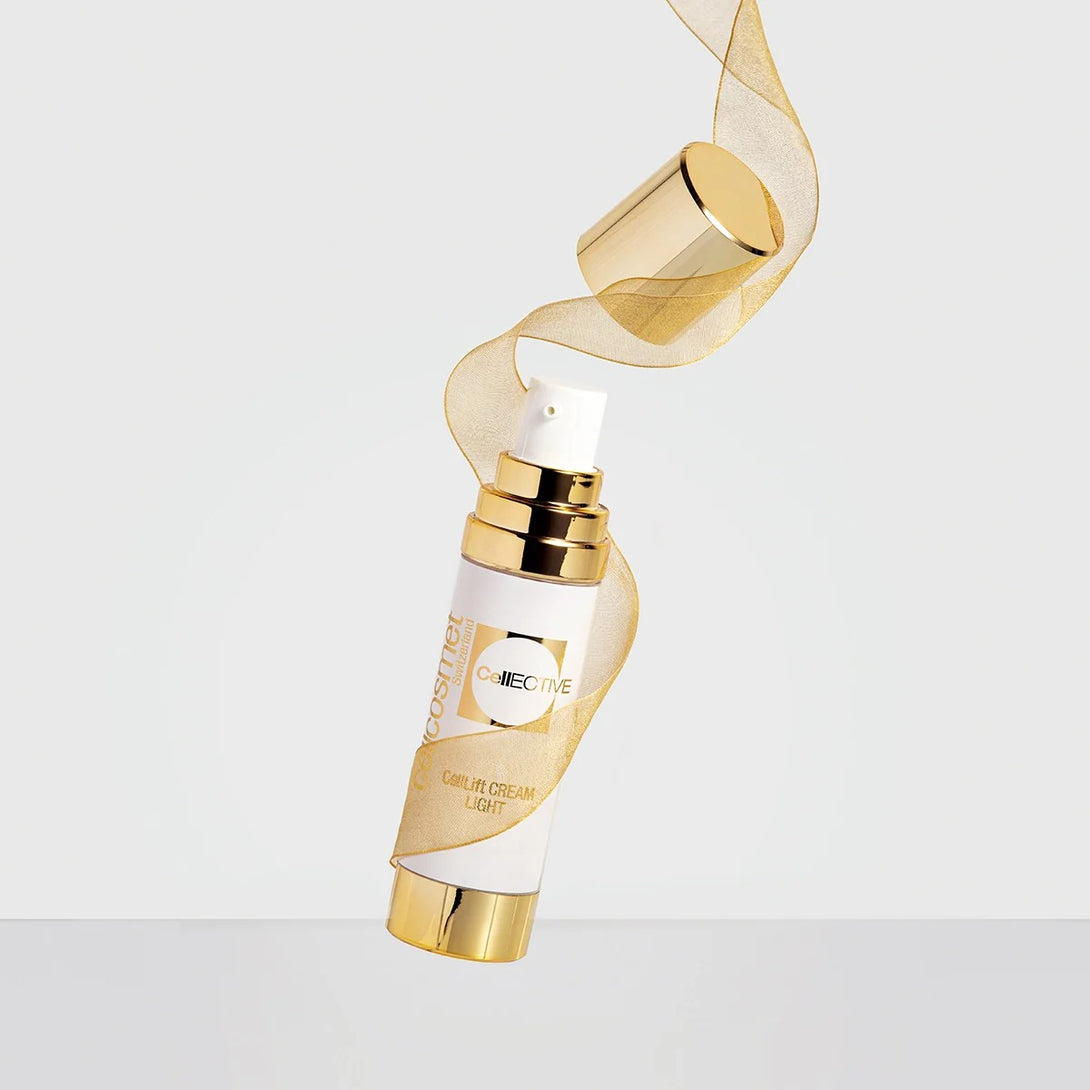 Gold and white cosmetic bottle with a gold ribbon on a light gray background