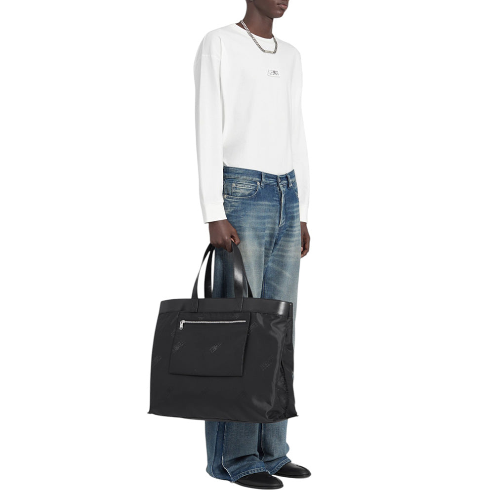 Person holding a black tote bag against a white background
