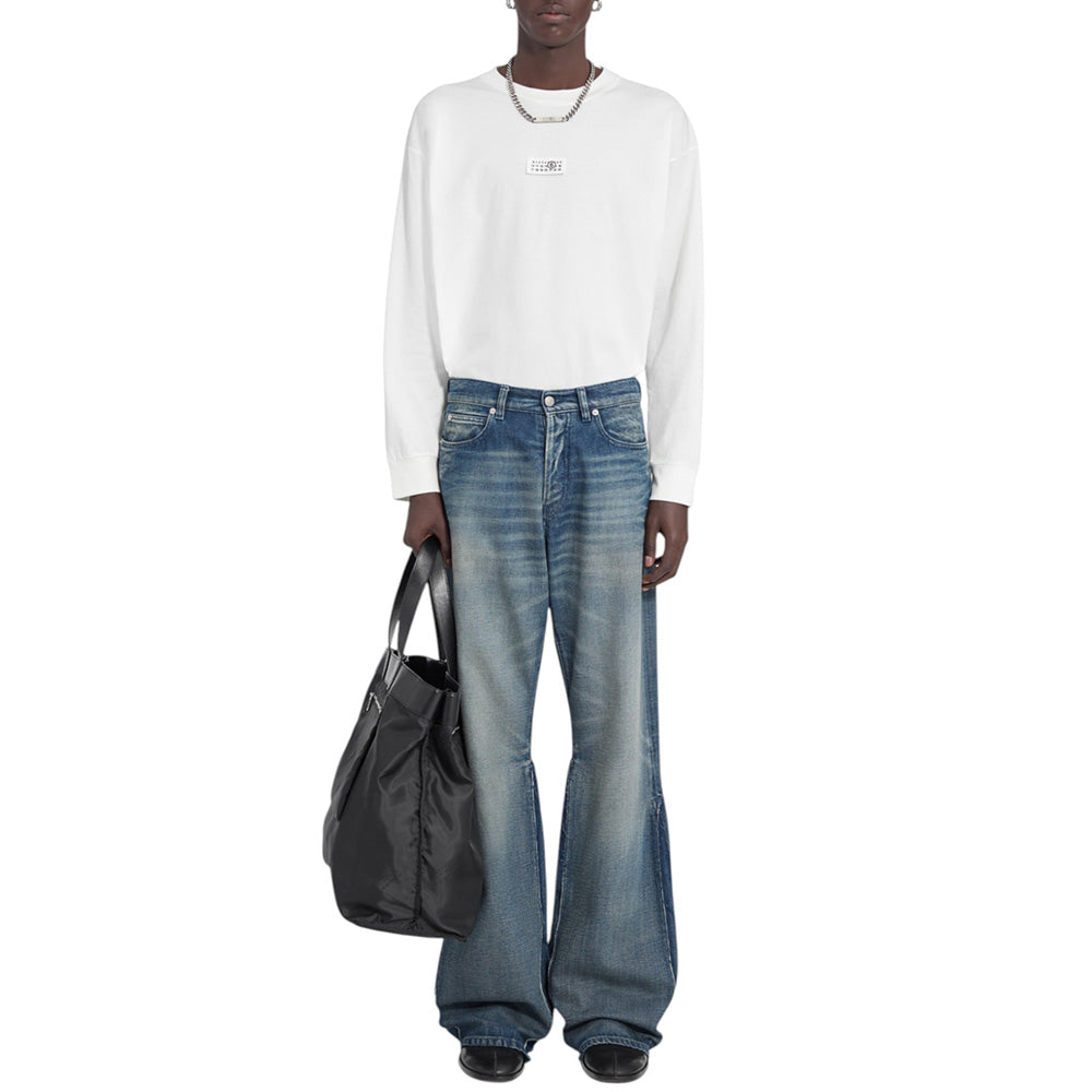 Person wearing a white long-sleeve shirt and blue jeans holding a black bag on a white background