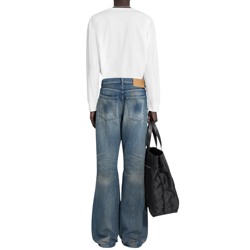 Person wearing blue jeans and a white shirt, holding a black bag on a white background