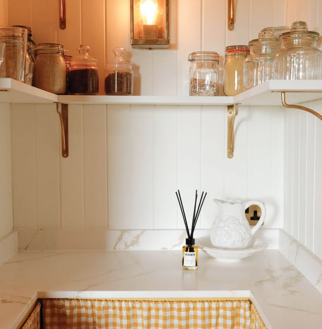 Cabinet interior with jars, a diffuser, and a pitcher on a marble countertop.