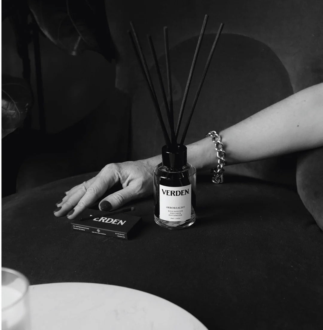 Verden diffuser bottle on a table with a hand and bracelet in the background