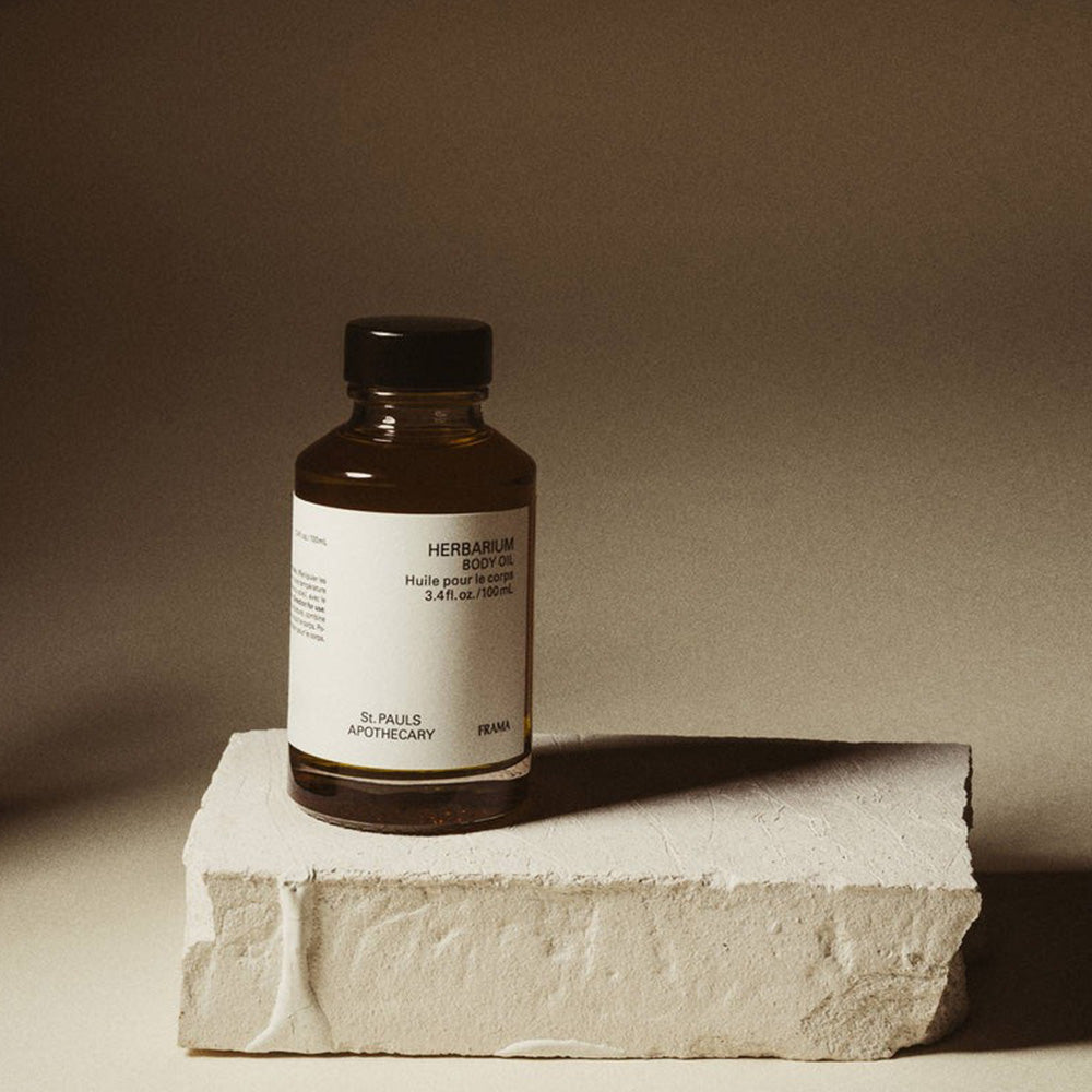 Bottle of St. Paul's Apothecary herbal balm oil on a stone surface with a beige background